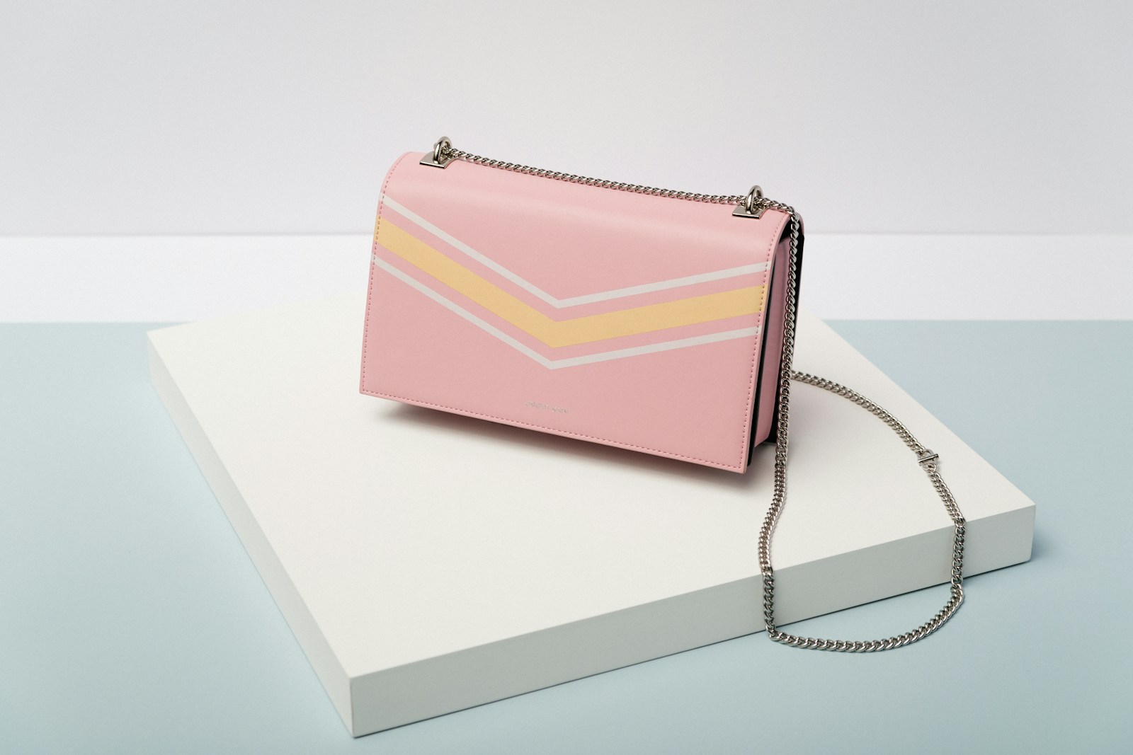 Contemporary curved designer handbag resting on travertine